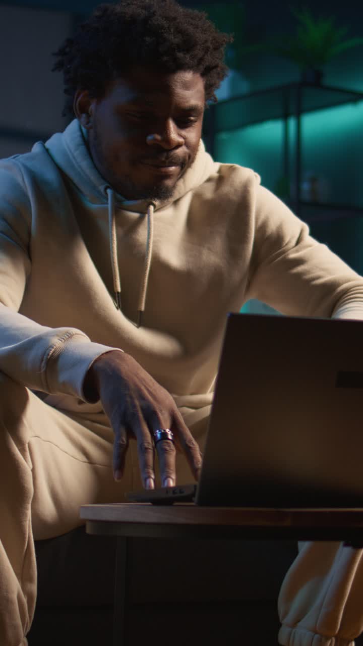 African American Man Sitting on Couch and Typing on Laptop