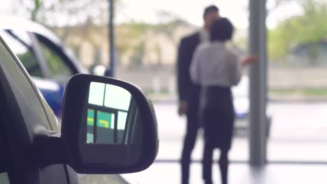 vista desenfocada de un hombre hablando con una mujer concesionaria de automóviles. joven hombre confiado eligiendo automóvil en la sala de exposiciones