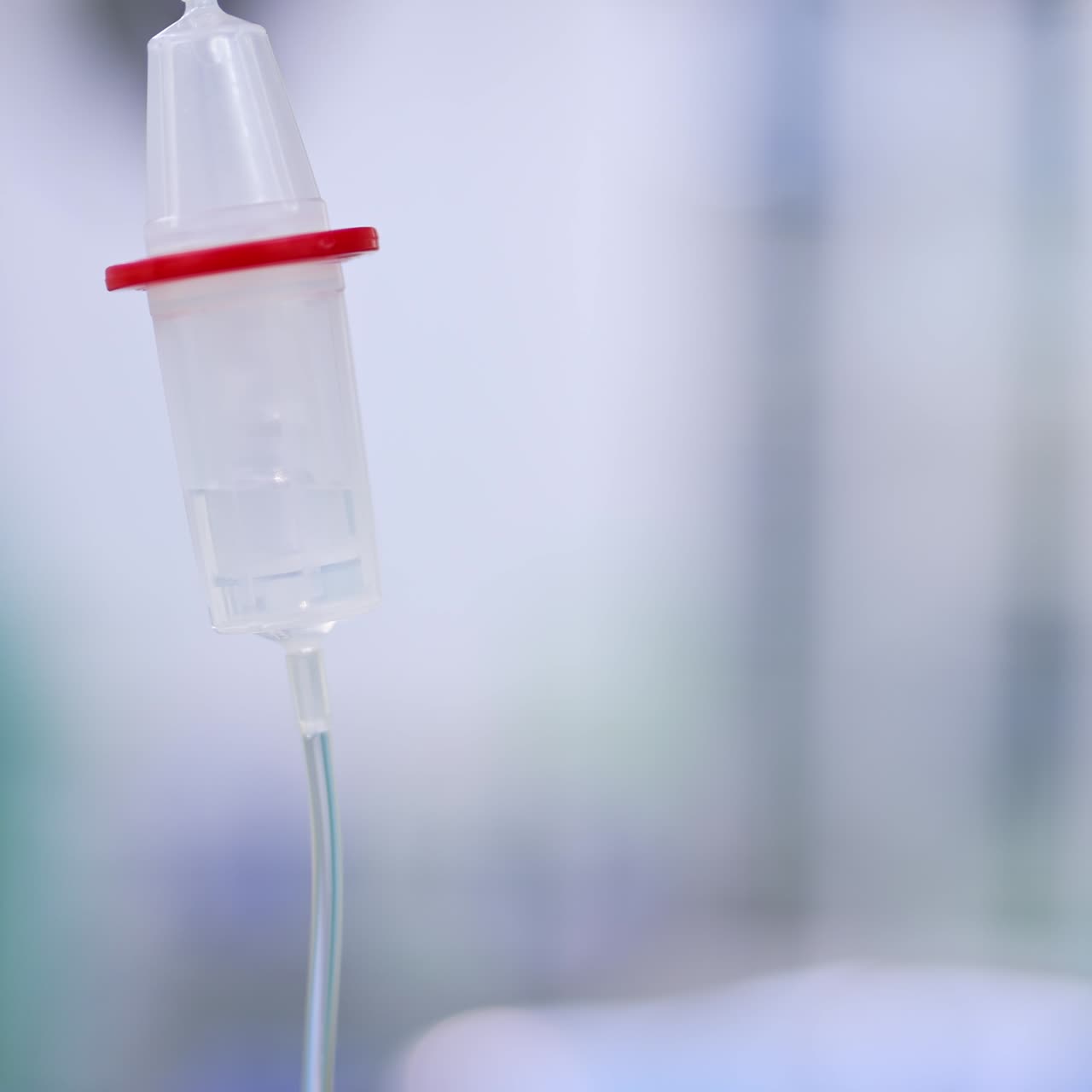 Medication reservoir of drop counter in operational room. Close up. Figure of a doctor moving at backdrop in blur