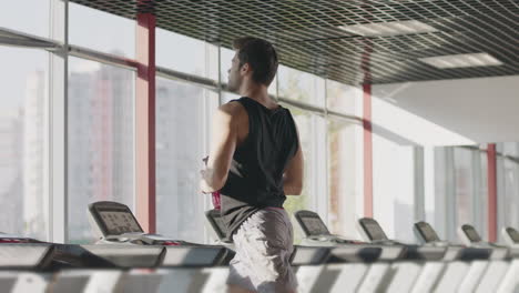 Runner-man-drinking-water-from-bottle-at-intensive-training-on-treadmill-machine