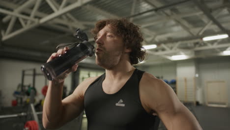 athletic man drinking water from bottle in gym