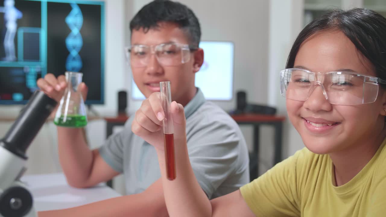 Young Asian Boy And Girl Smiling To Camera While Holding Tubes In Classroom. Study With Scientific Equipment. Education Concept