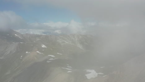 Drone-flying-through-thick-clouds-and-revealing-beautiful-mountain-landscape