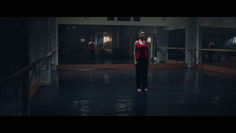 a young woman practices modern dancing and ballet in a moody room full of mirrors