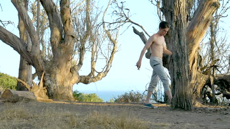 joven sin camisa trotando en cámara lenta durante un entrenamiento en los acantilados con vistas al océano pacífico azul en santa bárbara, california