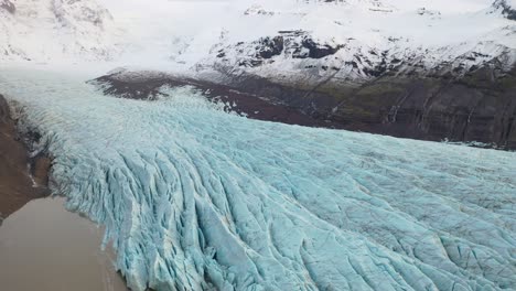 aerial of a glacier frozen by a snowcovered mountain range in iceland 1