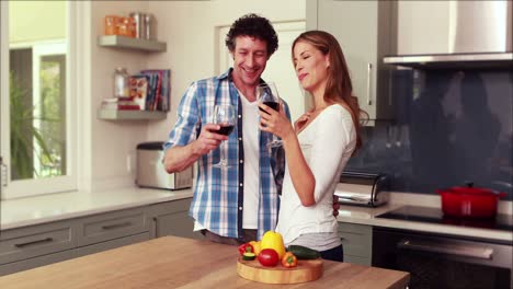 pareja feliz cortando verduras y bebiendo vino