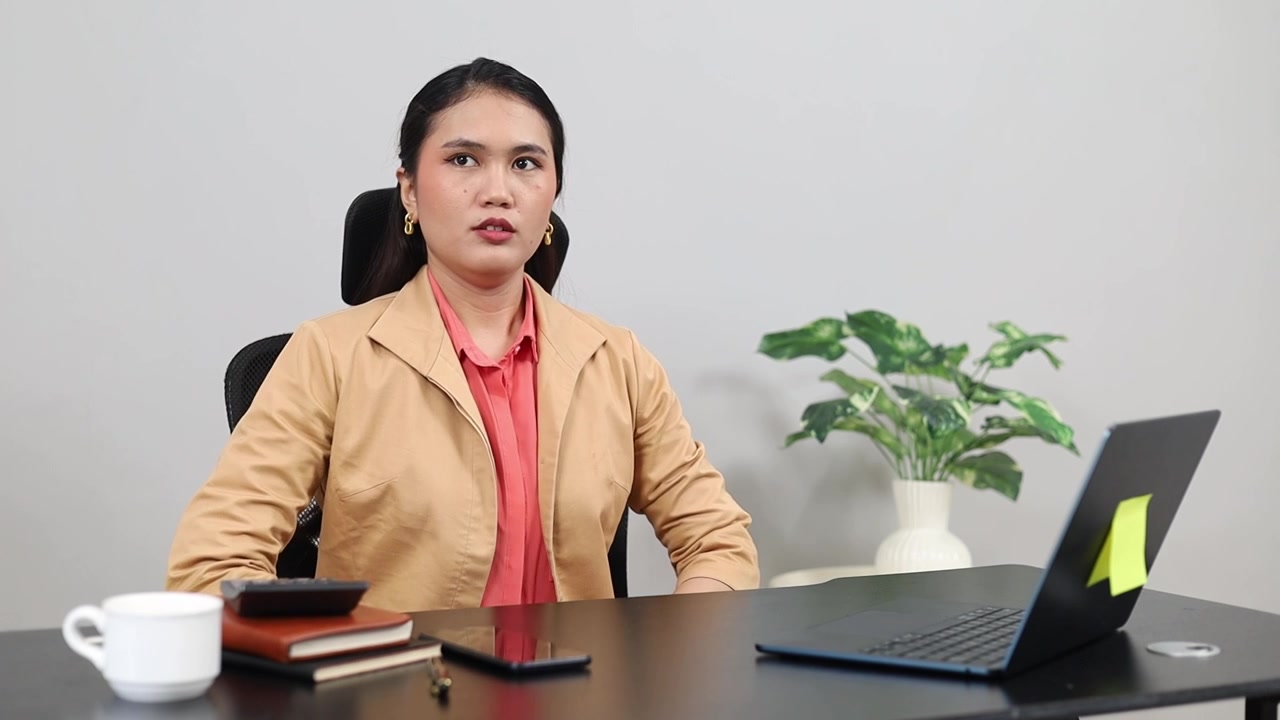 A young Asian businesswoman gets ready for work, sitting at her office desk.