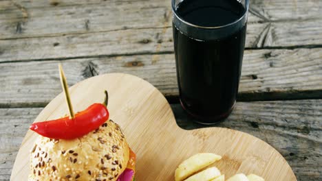 hamburguesa, papas fritas y bebida fría en una tabla de madera