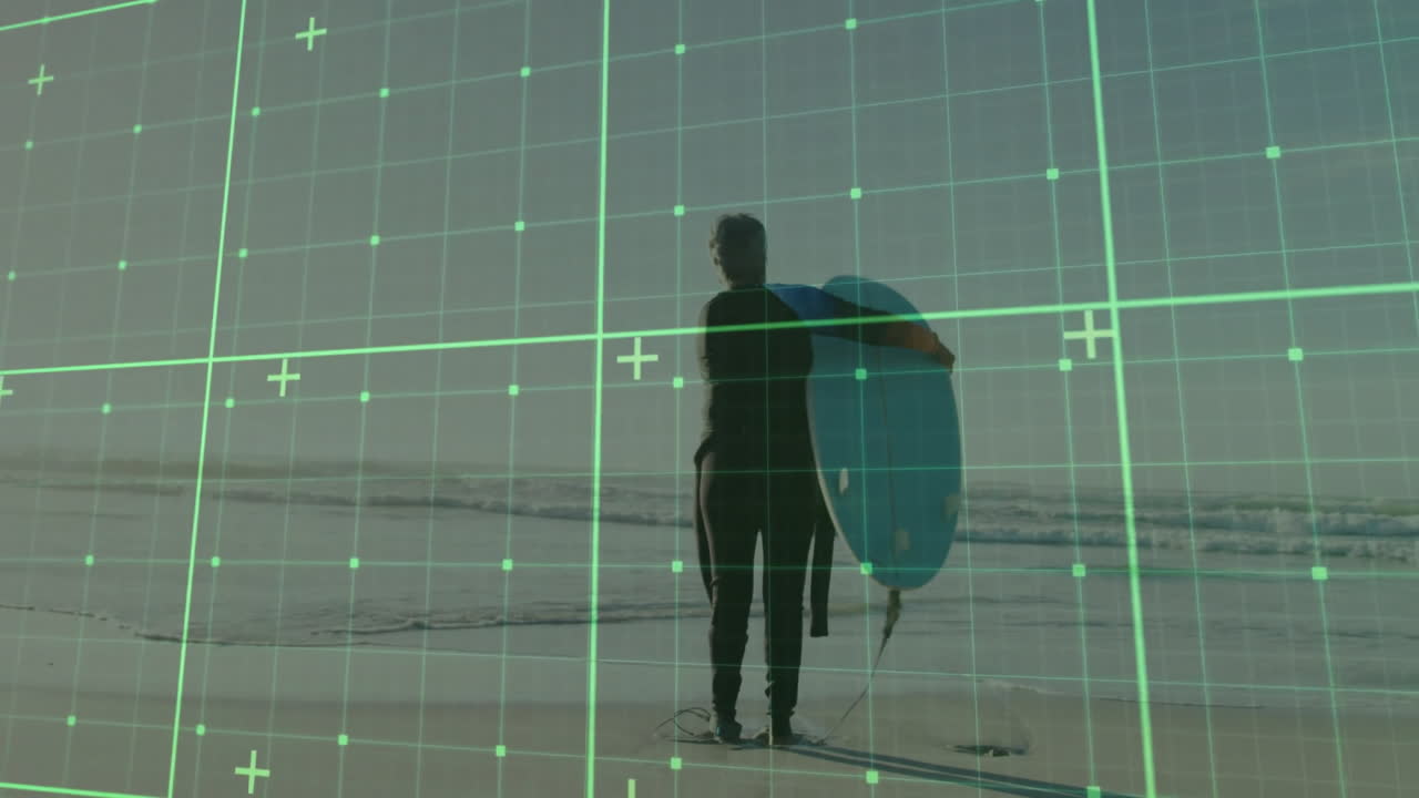 Male surfer standing on beach, holding surfboard under arm, showing augmented reality grid