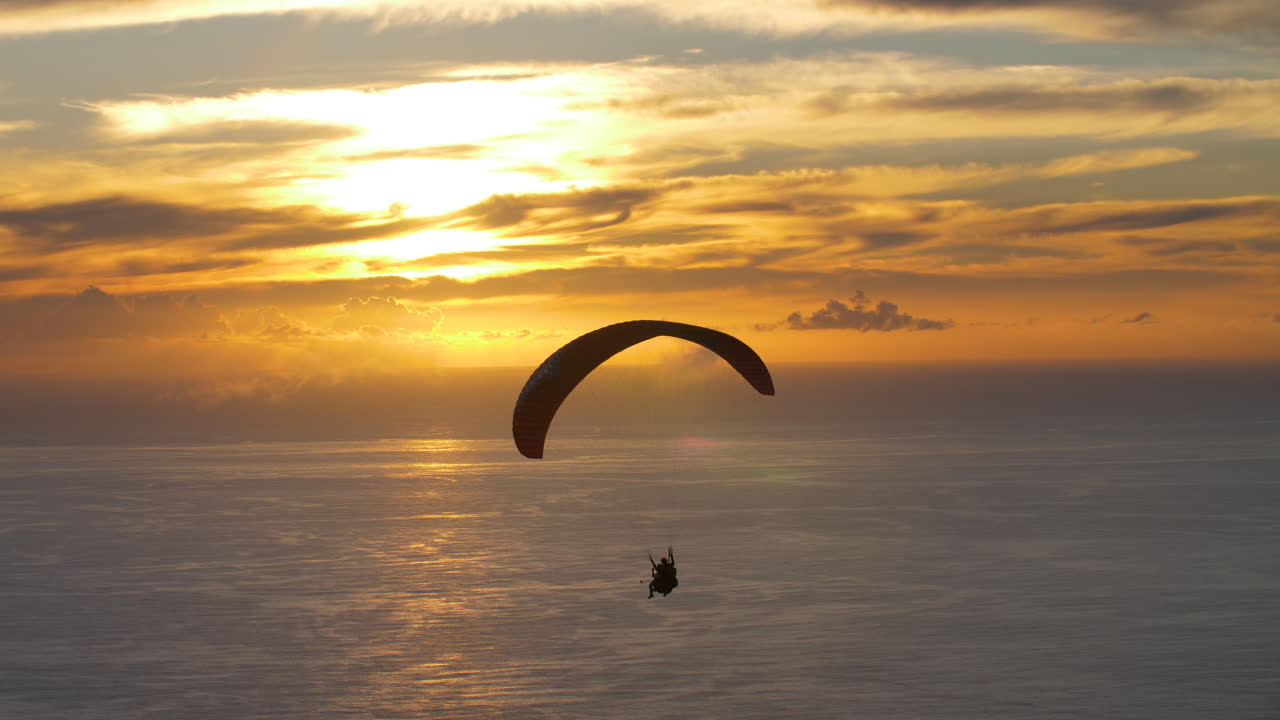 el parapente navega a través del cielo dorado mientras el sol se pone sobre el océano
