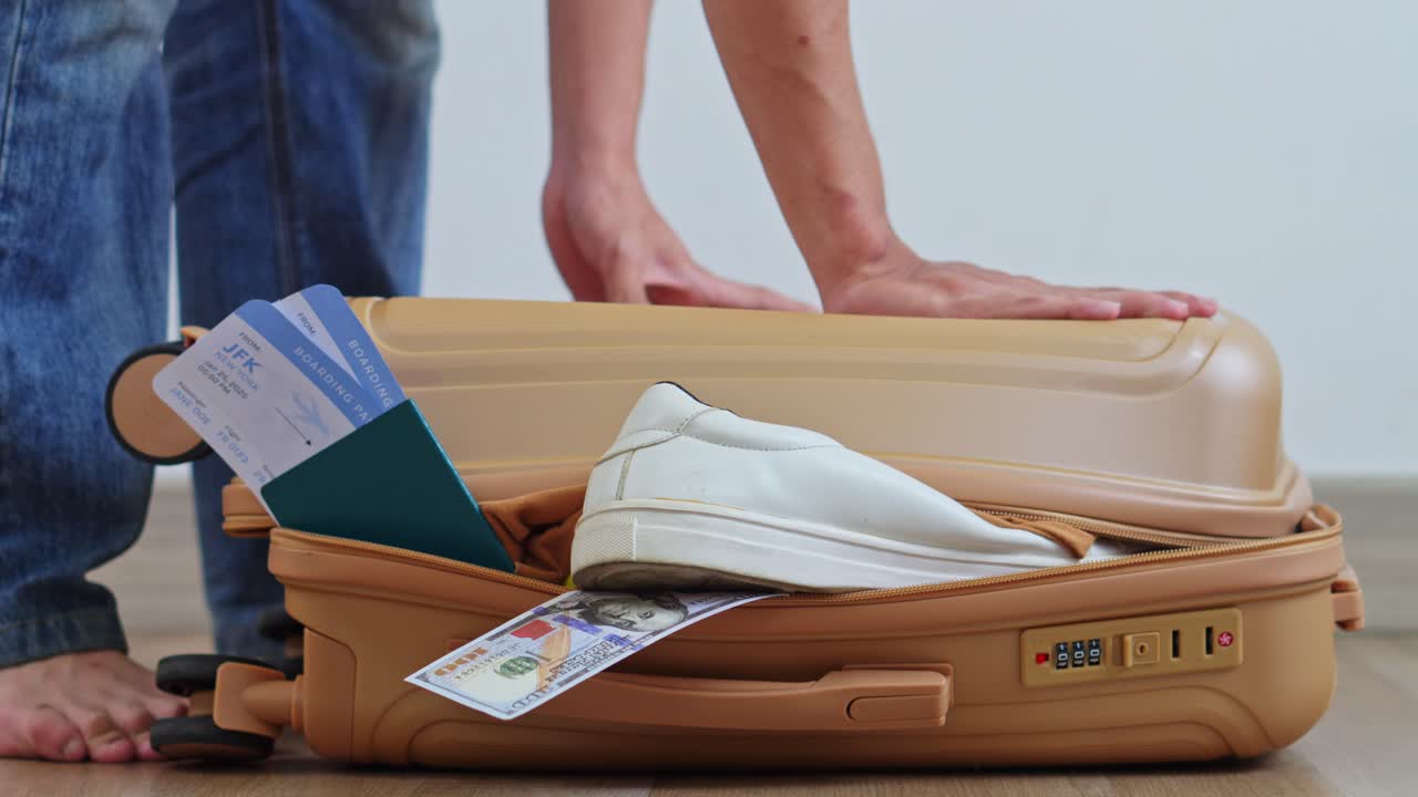Gros plan des mains d'un voyageur appuyant sur une valise sur le point de céder.