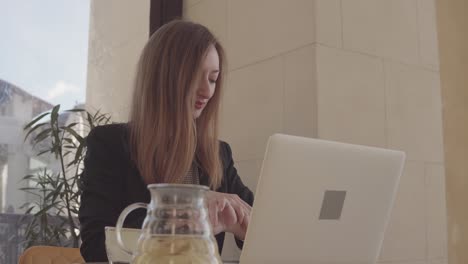 mujer trabajando en una computadora portátil en un café