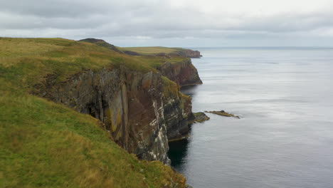 Drone-shot-of-Whaligoe-Haven-passing-by-the-rocky-250ft-cliffs-overlooking-the-north-sea-in-Scotland