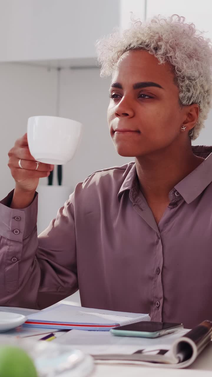Young professional woman enjoys a quiet coffee break at her desk in office
