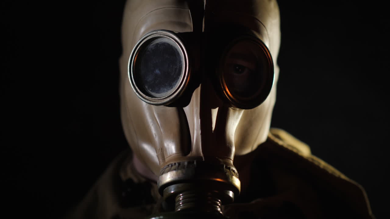 I bagliori del fuoco si riflettono nell'occhio e nella maschera antigas dell'uomo