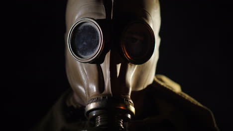 the gleams of the fire are reflected in the eye and gas mask of the man