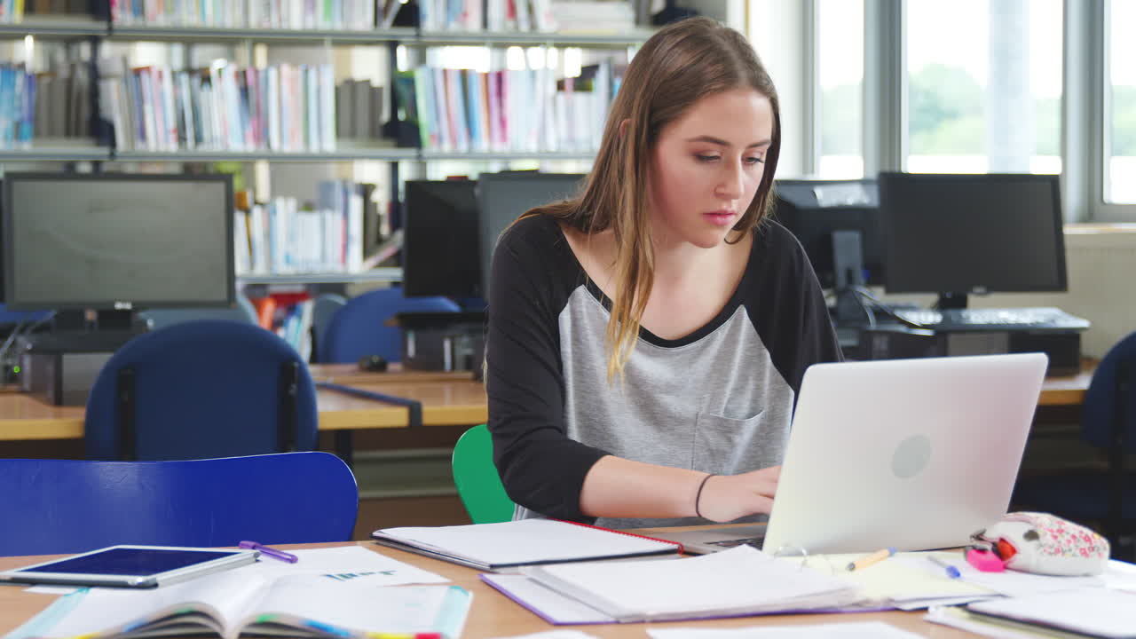 estudiante trabajando en la computadora en la biblioteca de la universidad