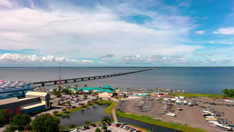 Vista-De-Drones-Volando-Sobre-La-Escuela-Secundaria-De-Destino,-El-Restaurante-De-Mariscos-De-Lulu-Y-El-Legendario-Marino-Hacia-El-Puente-Mid-Bay