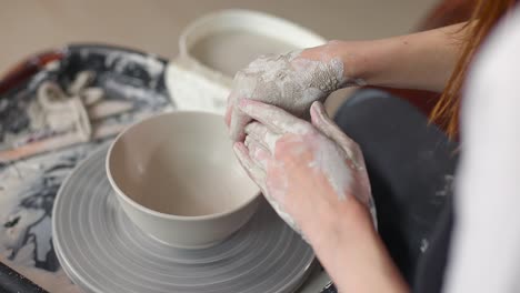 close-up of the hand of a master potter working on a potter's wheel, forming a bowl of clay. slow motion