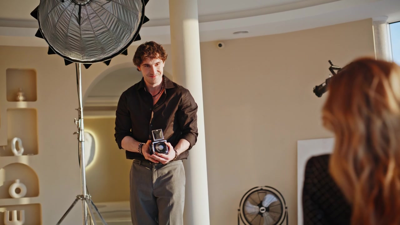 Photographer holding vintage film camera studio. Man working fashion photoshoot.