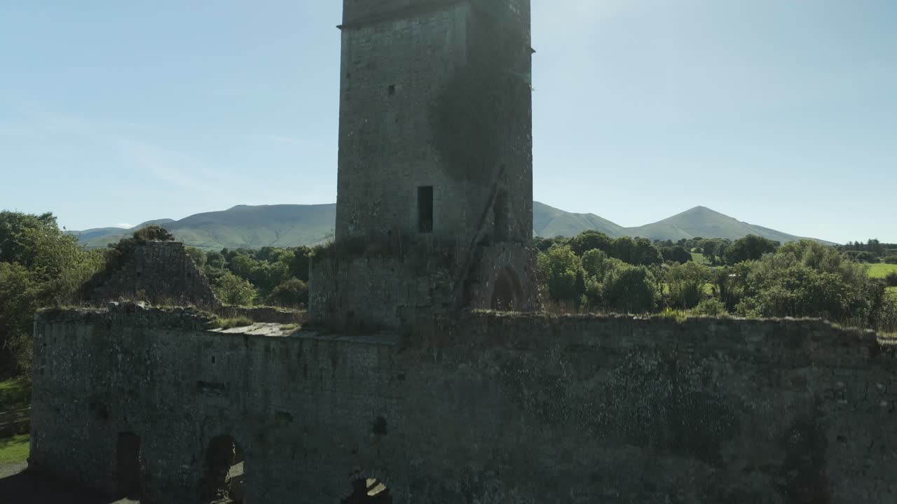 Moor abbey ruins with green fields and distant mountains in county tipperary, ireland , aerial view