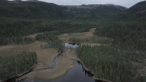 Hildremsvatnet,-Trondelag-County,-Norway---A-Serene-Lake-Enveloped-by-Verdant-Surroundings,-With-a-Distant-Mountain-Range-Completing-the-Tranquil-Panorama---Aerial-Pullback