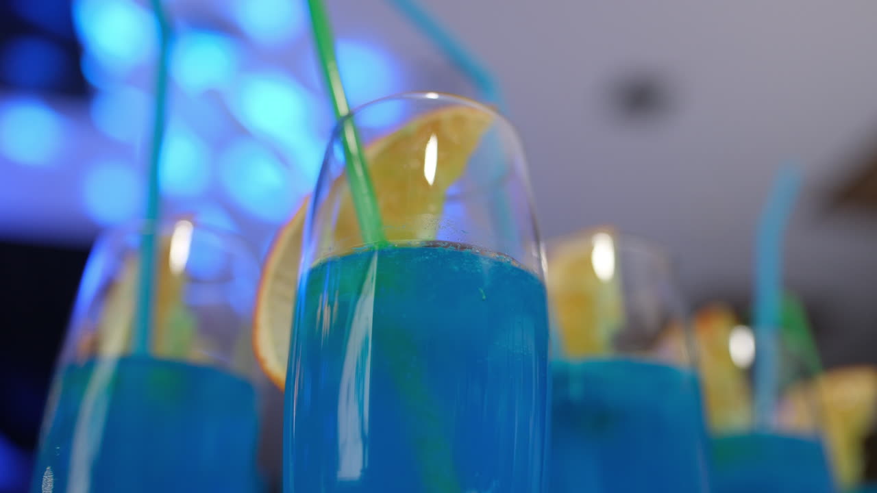 Cocktail alcolici blu con fette d'arancia e cannucce su un tavolo a una festa