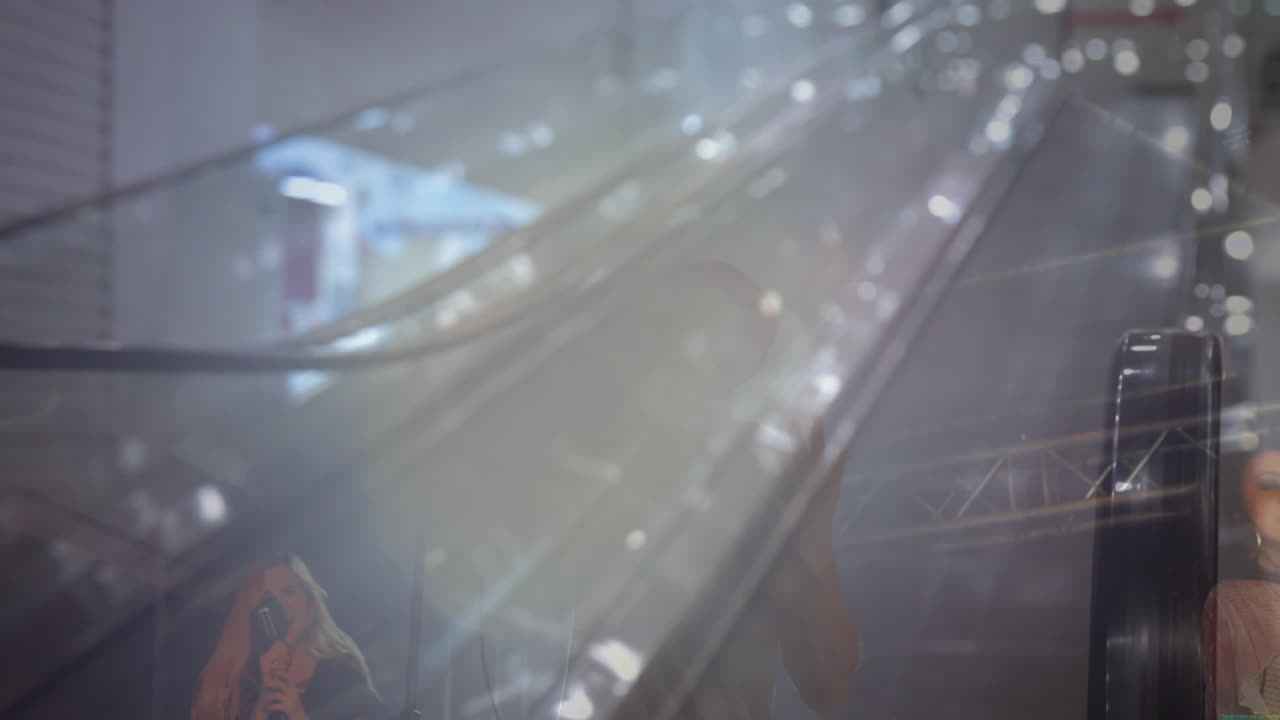 Woman singing into microphone overlaying travel escalator while man gesturing and suitcase rolling