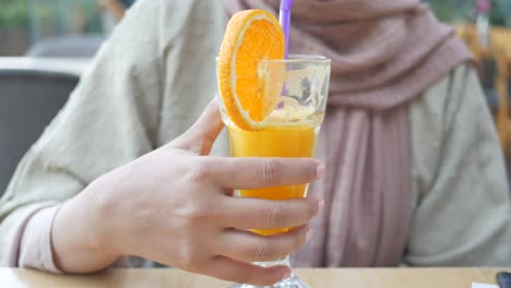 mujer sosteniendo un vaso de jugo de naranja