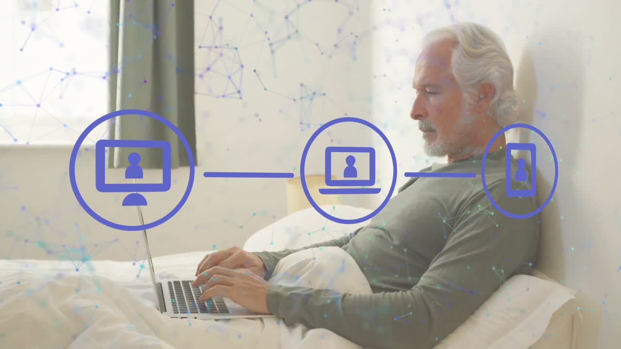 Mature man typing laptop on bed, monitor icon appearing and device icons showing network tech