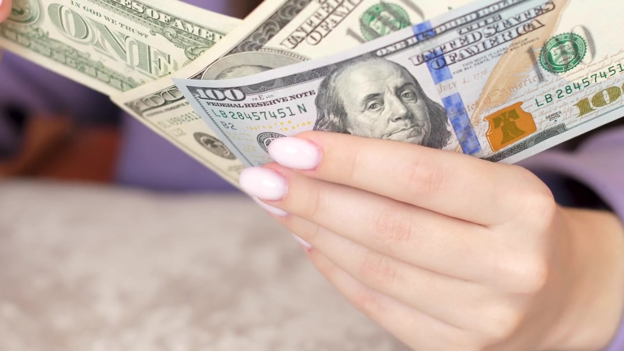 close-up of female hands with manicure on nails hold and count 100, one american dollars banknotes.woman counts money cash dollars.Selective focus