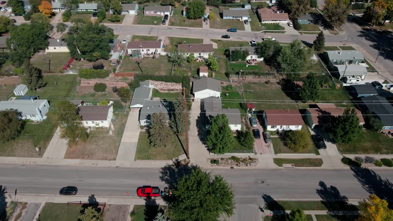 Drone footage moving parallel with a street revealing homes in a neighborhood