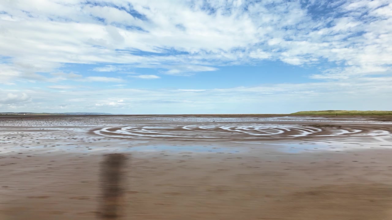 Point of view shot driving on the road to Holy Island over the causeway on the coast of Northumberland