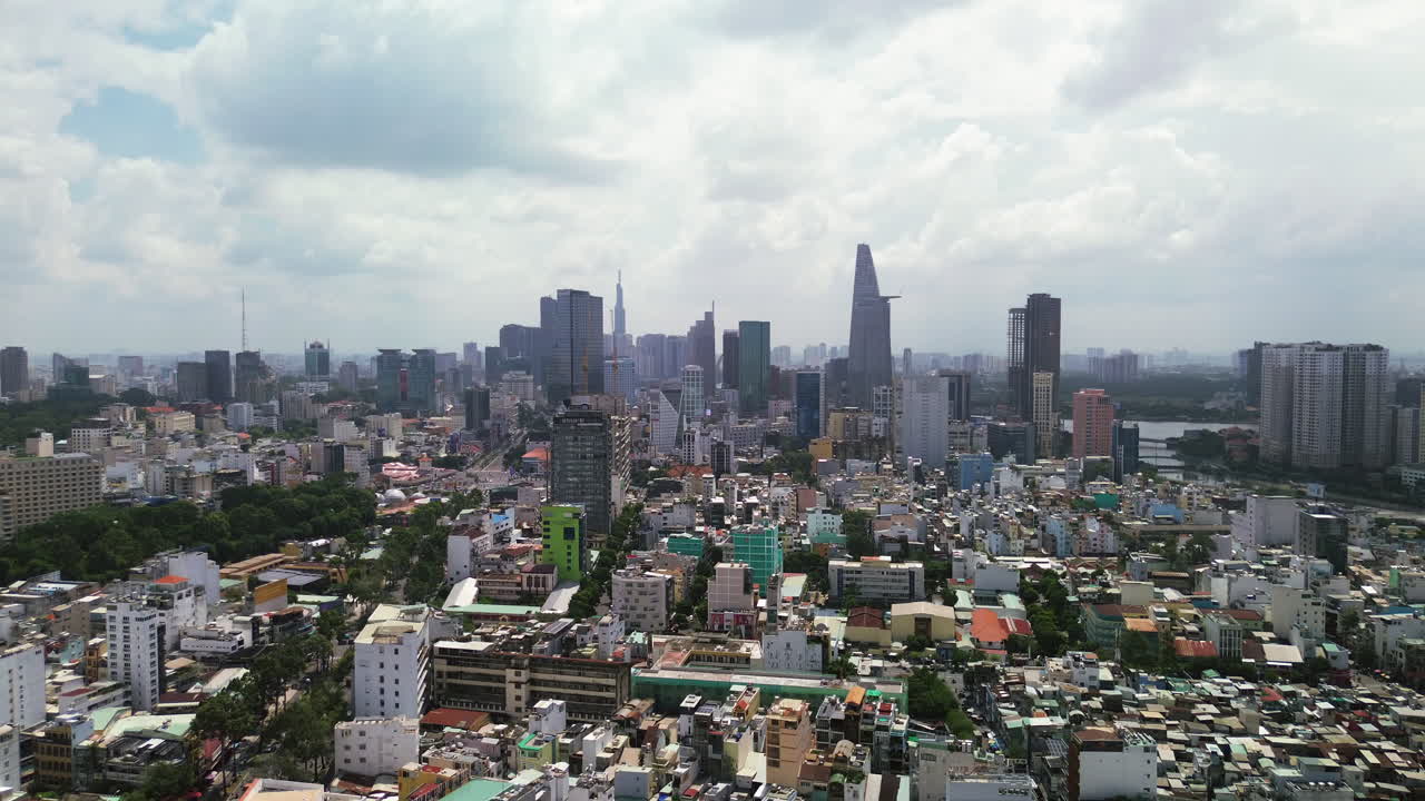 Wide aerial panoramic of Ho Chi Minh City skyline with dense urban buildings and cloudy sky, establishing dolly