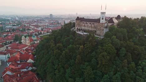 toma cinematográfica del castillo de ljubljana cuando el sol se levanta sobre la ciudad
