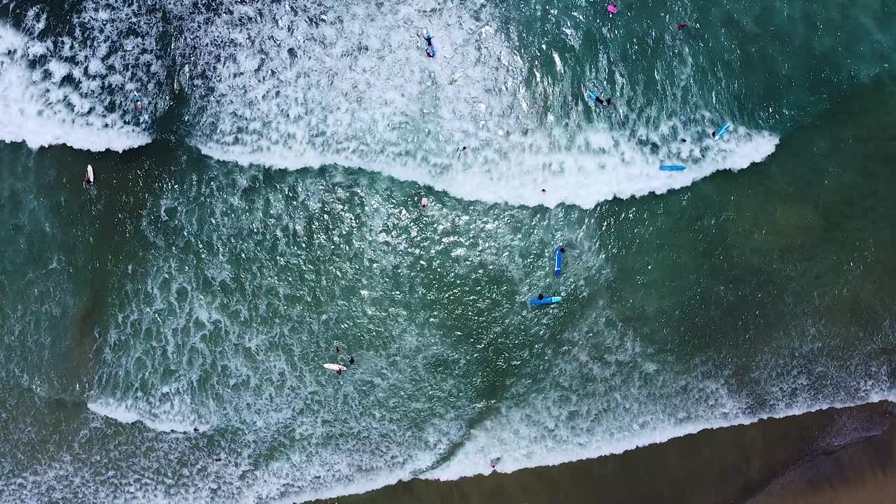 Surfers surfing on surfboards in clear turquoise shallow water at popular vacation spot