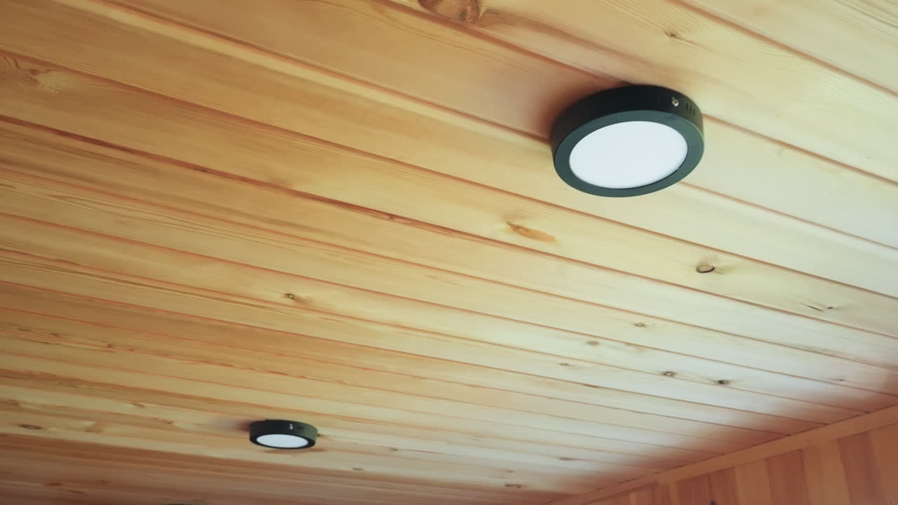 Close up of smooth wooden ceiling with round LED lights evenly spaced, emphasizing warm wood grain, natural knot patterns, and subtle lighting details in clean cozy indoor environment