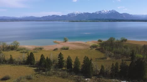 vista aérea escénica de 4k sobre el famoso lago chiemsee de baviera en el campo rural con un hermoso cielo azul, agua azul y verde clara, caña y las montañas de los alpes en el fondo en un día soleado