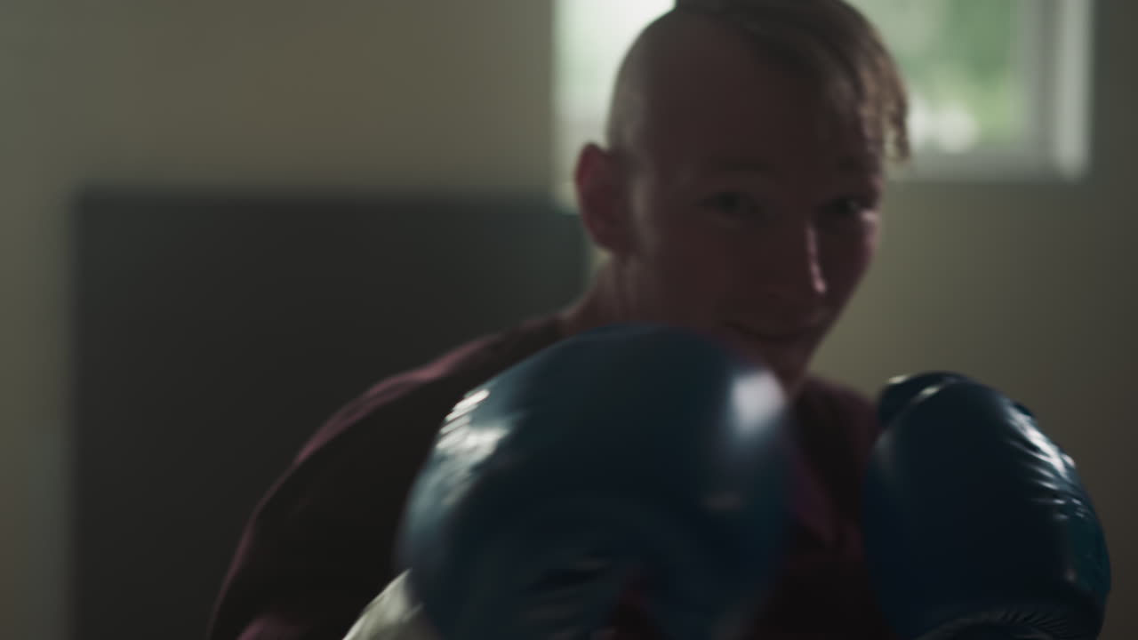 운동 선수는 스포츠 클럽에서 후크와 업퍼커트 훈련을 보여줍니다. 프로 권투 선수는 체육관에서 스로우 모션에서 카메라 앞에서 치를 훈련시니다. 무술 연습