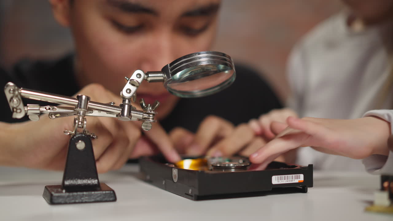 Asian technician with schoolgirl examines hard disk drive