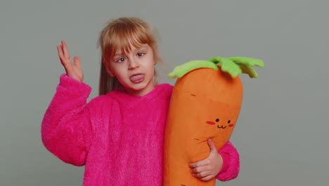 a young girl smiling and holding a carrot plush toy