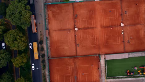 Fotografía-Cenital-De-Canchas-De-Tenis-Una-Al-Lado-De-La-Otra-Cerca-De-Una-Calle-Concurrida