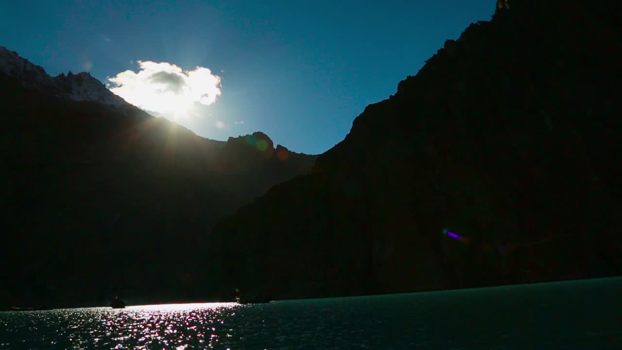 barcos en un magnífico lago azul rodeado de montañas cubiertas de nieve y sol, la vista más espectacular de la montaña con el lago