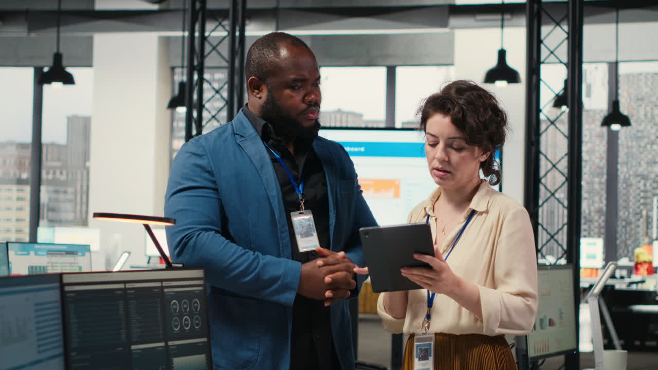Vertical Video Two employees reviewing data insights on tablet in professional workspace