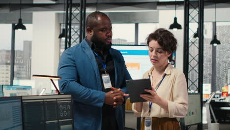vertical video two employees reviewing data insights on tablet in professional workspace