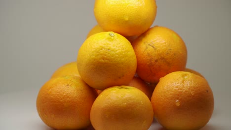 ten juicy oranges turning clockwise on a turntable - close up shot