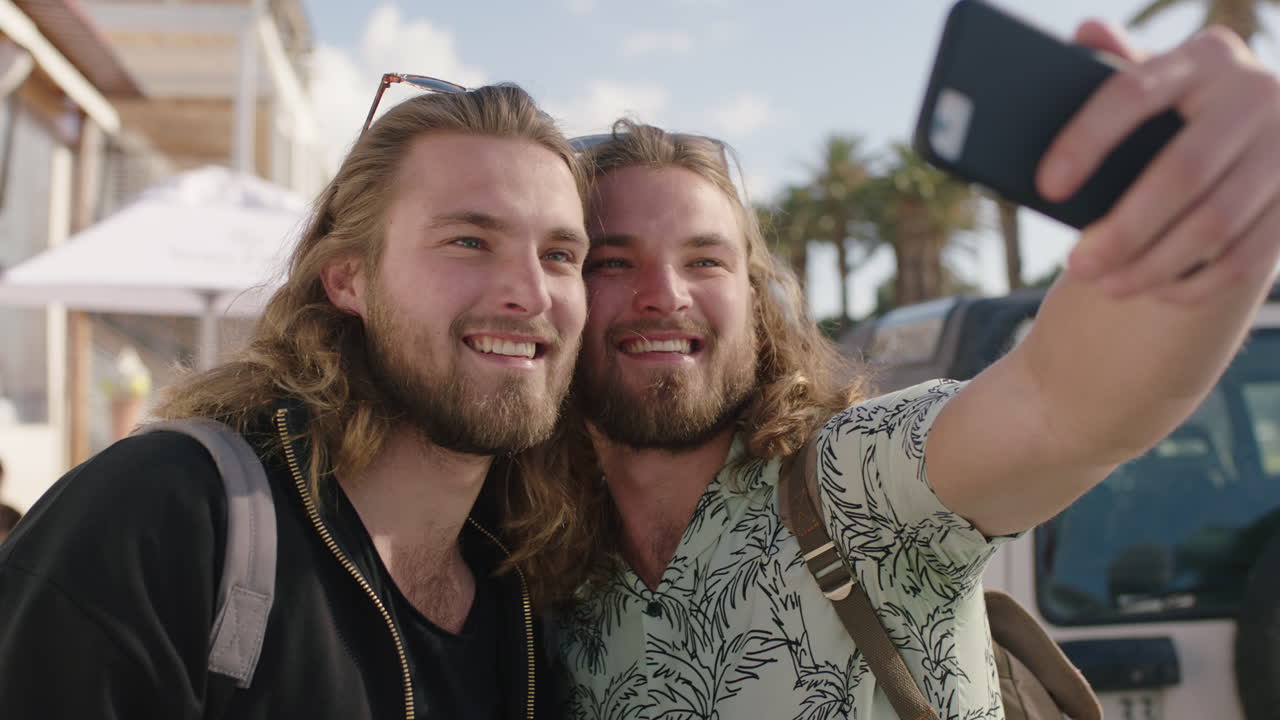 ritratto di affascinanti fratelli gemelli in vacanza che posano per un selfie insieme scattando una foto usando il telefono