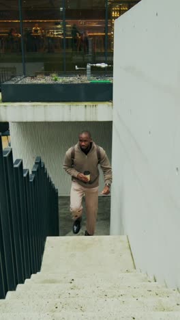 man walking up stairs with coffee