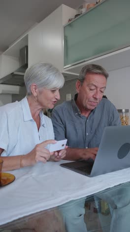 older couple using laptop and credit card for online shopping
